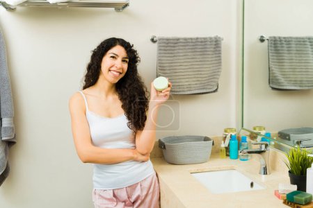 Téléchargez les photos : Belle femme latine utilisant un savon végétalien bio dans la salle de bain et souriant avant de se laver le visage - en image libre de droit