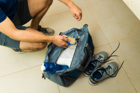 Photo for Close up of a young man putting soap and hygiene products in the gym bag to wash after exercising - Royalty Free Image