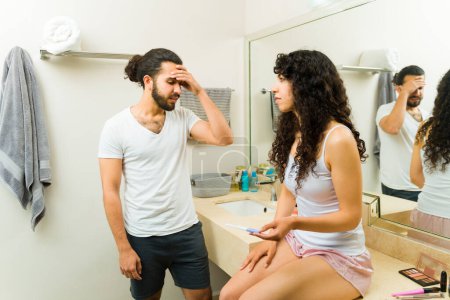 Foto de Preocupada pareja estresada que tiene problemas en el baño mientras miran la prueba de embarazo juntos - Imagen libre de derechos