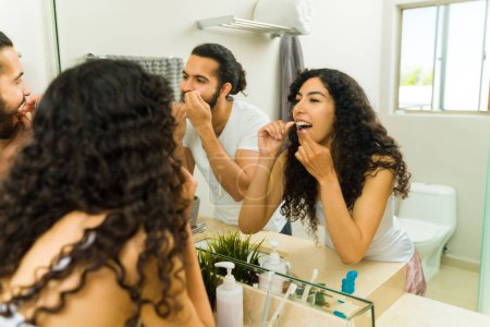 Téléchargez les photos : Beau jeune homme et femme avec hygiène dentaire en soie dentaire le matin ensemble - en image libre de droit