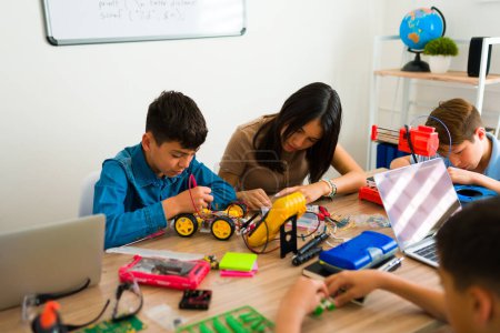 Téléchargez les photos : Groupe latin d'adolescents construisant des robots tout en construisant des circuits électroniques et en apprenant le codage pendant un projet - en image libre de droit
