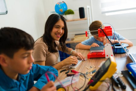 Photo for Excited young girl student laughing looking happy while building electronics for her robotics class - Royalty Free Image