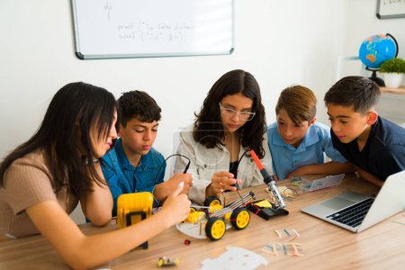 Téléchargez les photos : Étudiants adolescents intelligents intéressés par un projet collaboratif et le travail d'équipe lors d'un cours de robotique et la fabrication d'un prototype - en image libre de droit