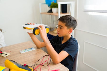 Téléchargez les photos : Jeune garçon adolescent construisant un robot électronique ou un prototype pendant son cours de robotique au collège - en image libre de droit