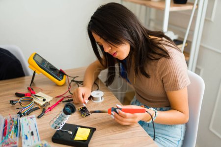 Téléchargez les photos : Adolescente jeune fille utilisant un voltmètre lors de la construction d'un circuit ou d'une planche à pain pendant un cours électronique - en image libre de droit