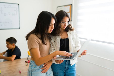 Photo for Beautiful latin teen girls working on a collaborative project and programming robots on the computer while learning to code - Royalty Free Image