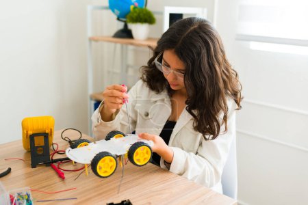 Téléchargez les photos : Adolescente jeune fille avec des lunettes construire un robot et apprendre la programmation dans son cours d'électronique au collège - en image libre de droit