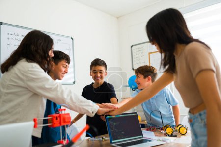 Téléchargez les photos : Smart groupe excité d'étudiants adolescents prêts à faire un high five après avoir terminé leur projet de collaboration robotique ensemble - en image libre de droit