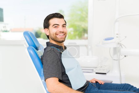 Foto de Retrato de un joven latino y paciente sonriendo al dentista y luciendo feliz después de un tratamiento blanqueador - Imagen libre de derechos