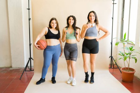 Foto de Ajuste diversas mujeres jóvenes en ropa deportiva haciendo contacto visual listo para jugar baloncesto o deportes durante un entrenamiento - Imagen libre de derechos