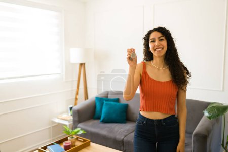 Foto de Alegre hermosa mujer sonriendo mirando emocionada mientras muestra sus nuevas llaves de la casa después de mudarse a su casa - Imagen libre de derechos