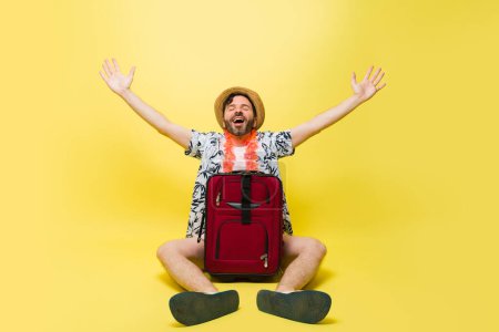 Foto de Relajado hombre feliz relajante buscando emocionado de viajar con una maleta y listo para ir a la playa en frente de un fondo de estudio - Imagen libre de derechos