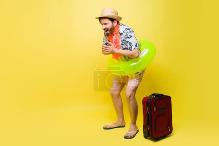 Téléchargez les photos : Bel homme mi-adulte portant un short avec un gonflable prêt à aller à la piscine pendant ses vacances d'été - en image libre de droit