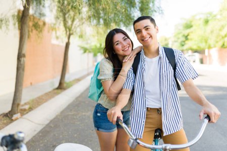 Photo for Happy attractive couple in love hugging while going on a bike ride together outdoors while enjoying their summer leisure time - Royalty Free Image