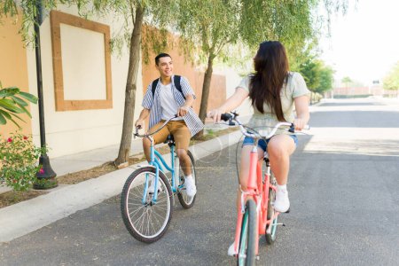 Foto de Diversión joven mujer y hombre hablando en una cita mientras montan sus bicicletas juntos al aire libre durante un tiempo de ocio en verano - Imagen libre de derechos