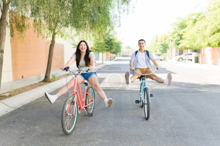 Foto de Emocionado joven feliz mujer y hombre jugando a montar sus bicicletas vintage y divertirse juntos en una cita al aire libre - Imagen libre de derechos