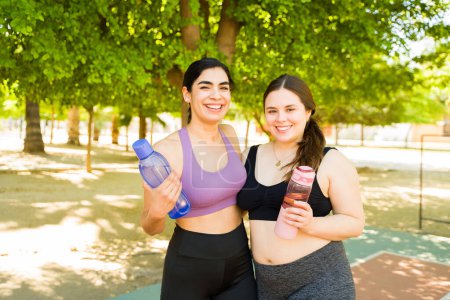 Photo for Portrait of attractive plus size women smiling looking happy while carrying water bottles to start working out or exercise outdoors - Royalty Free Image