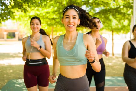 Photo for Hispanic attractive women smiling looking happy making eye contact while enjoying her sporty run and workout in the park with her friends - Royalty Free Image