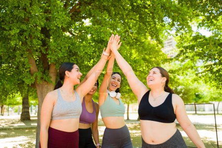 Foto de Emocionado grupo de diversas mujeres haciendo un high five celebrando terminar su carrera juntos o ejercicios que promueven la aceptación del cuerpo - Imagen libre de derechos