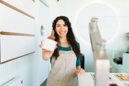 Photo for Hispanic cheerful woman working selling delicious chocolate ice cream at the frozen yogurt shop and looking very happy - Royalty Free Image