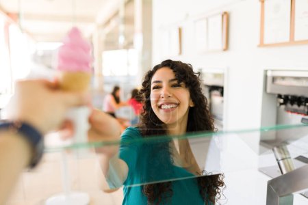 Photo for Young smiling woman buying and ready to eat strawberry ice cream cone for a cold sweet treat during the summer - Royalty Free Image
