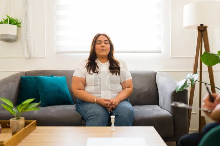 Foto de Mujer ansiosa haciendo ejercicios de respiración para relajarse mientras recibe consejos para su depresión y ansiedad con un terapeuta - Imagen libre de derechos