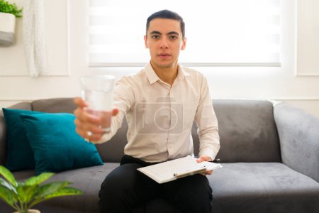 Téléchargez les photos : Psychologue professionnel masculin en contact visuel offrant un verre d'eau à un patient lors d'une séance de thérapie - en image libre de droit