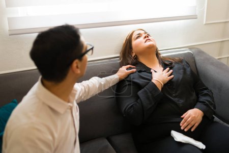 Foto de Psicólogo o psiquiatra que ayuda a una paciente que sufre un ataque de ansiedad y dolor en el pecho mientras está en terapia - Imagen libre de derechos