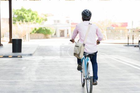 Téléchargez les photos : Homme d'affaires vu de derrière en vélo écologique à l'extérieur dans la ville urbaine pendant son trajet vers le travail - en image libre de droit