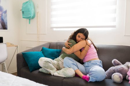 Foto de Adolescentes mejores amigos llorando mirando triste mientras se abrazan y se reconfortan en casa debido a problemas adolescentes - Imagen libre de derechos