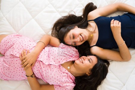 Foto de Feliz hermosa adolescente niñas y mejores amigos riendo mientras hablan y bromeando en sus pijamas durante una divertida fiesta de pijamas - Imagen libre de derechos