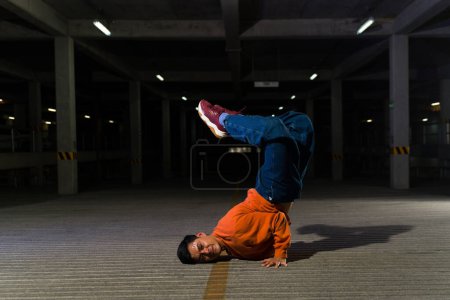 Photo for Talented urban dancer and street performer doing a freestyle performance and breakdance choreography in a parking lot - Royalty Free Image