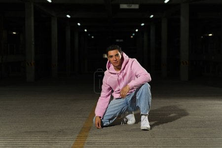 Foto de Retrato de un atractivo hombre latino y bailarín listo para una actuación de estilo libre en un estacionamiento oscuro o danza hip hop - Imagen libre de derechos