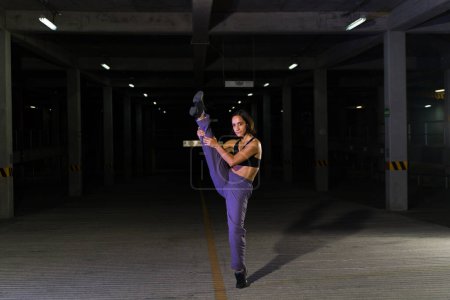 Photo for Attractive urban street female dancer dancing in a dark parking garage and looking cool and funky - Royalty Free Image