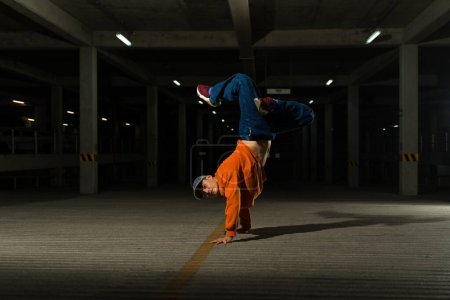 Photo for Latin attractive male dancer breakdancing standing on his head and doing a freestyle street hip hop dance in the street - Royalty Free Image