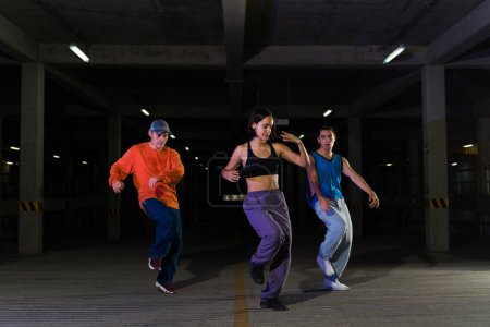Téléchargez les photos : Cool jeunes hommes et femmes dansant ensemble de la musique hip hop urbaine tout en faisant une performance de rue moderne funky - en image libre de droit