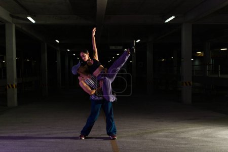 Photo for Couple of attractive urban dancers doing an artistic ballet dance performance at night in the street - Royalty Free Image