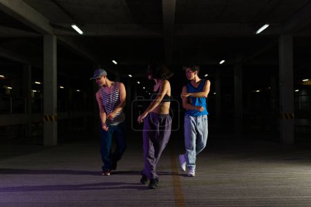 Photo for Attractive group of street performers dancing and doing a cool modern dance choreography in the street at night - Royalty Free Image