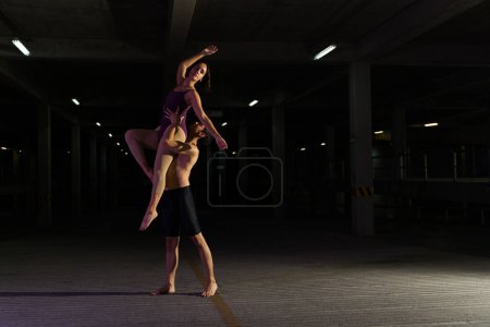 Photo for Beautiful young couple and artistic street dancers on a modern stage dancing classic ballet at night - Royalty Free Image