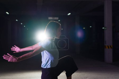 Foto de Perfil de un artista urbano en acción bailando por la noche mientras hace una danza moderna fresca en el escenario - Imagen libre de derechos