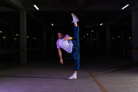 Téléchargez les photos : Danseuse de rue latine attrayante dansant sur le parking et exécutant dans la rue une danse moderne fraîche la nuit - en image libre de droit