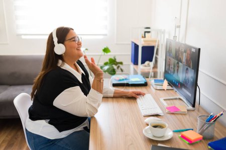 Foto de Emocionado más tamaño mujer buscando feliz mientras sonríe durante una videollamada de negocios de trabajo en su oficina - Imagen libre de derechos