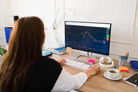 Téléchargez les photos : Femme d'affaires regardant un graphique de marché boursier sur l'ordinateur tout en investissant et en achetant des actions - en image libre de droit