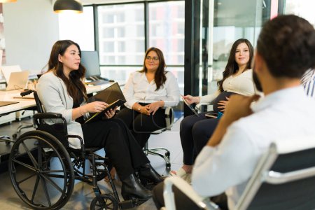 Téléchargez les photos : Gestionnaire handicapé avec un dossier de projet discutant avec le groupe de collègues assis dans le bureau de démarrage - en image libre de droit