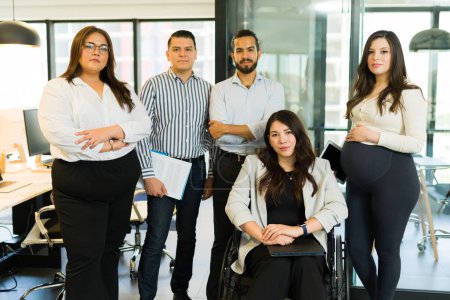 Téléchargez les photos : Femme handicapée gestionnaire en fauteuil roulant avec une équipe d'affaires diversifiée debout ensemble dans le bureau de démarrage - en image libre de droit