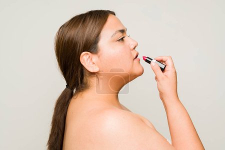 Photo for Profile of a large fat woman putting on lipstick with bare shoulders and getting ready to go out with a lot of self love - Royalty Free Image