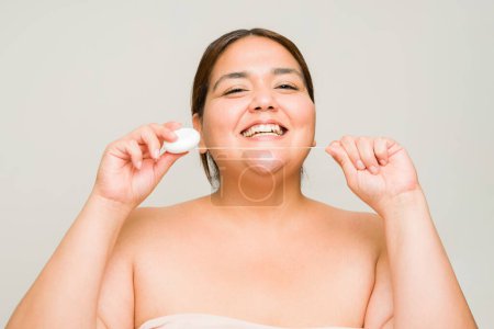 Foto de Mujer alegre con sobrepeso en sus 30 años usando hilo dental y sonriendo con los dientes blancos y sanos mirando emocionada - Imagen libre de derechos
