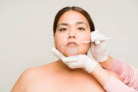 Foto de Hermosa mujer gorda haciendo un procedimiento cosmético poniéndose inyecciones de toxina botulínica o ácido hialurónico para prevenir el envejecimiento y las arrugas - Imagen libre de derechos