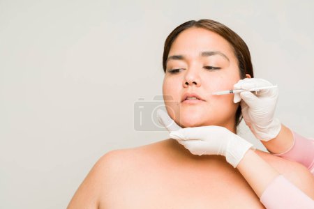 Foto de Preciosa mujer grande obesa con hombros desnudos que pone inyecciones de toxina botulínica o ácido hialurónico para su piel envejecida - Imagen libre de derechos