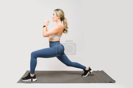 Téléchargez les photos : Attrayant athlète femme en leggings faire squats bulgares tout en travaillant sur son corps en forme et butin - en image libre de droit